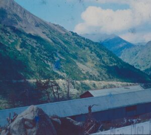 Roof valley with displaced shingles, exposed flashing, and damp debris after rainfall.